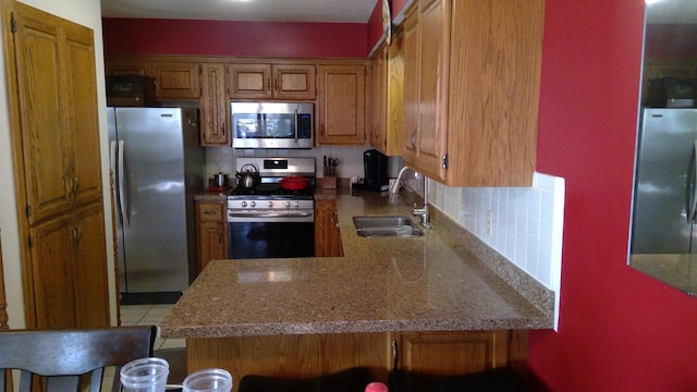 kitchen with stainless steel appliances, a kitchen bar, kitchen peninsula, tasteful backsplash, and sink