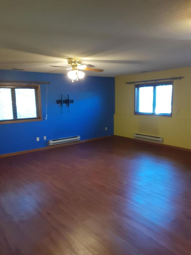 spare room featuring ceiling fan, baseboard heating, and dark hardwood / wood-style floors