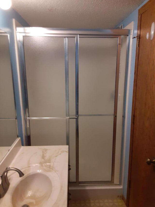 bathroom featuring an enclosed shower, a textured ceiling, and large vanity