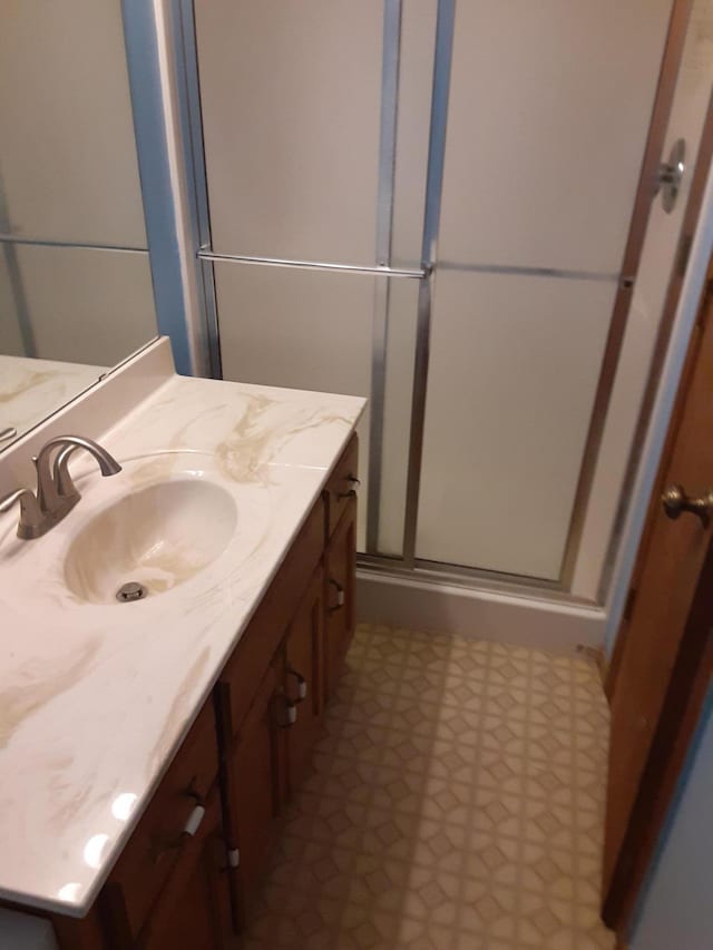 bathroom featuring tile floors, oversized vanity, and a shower with door