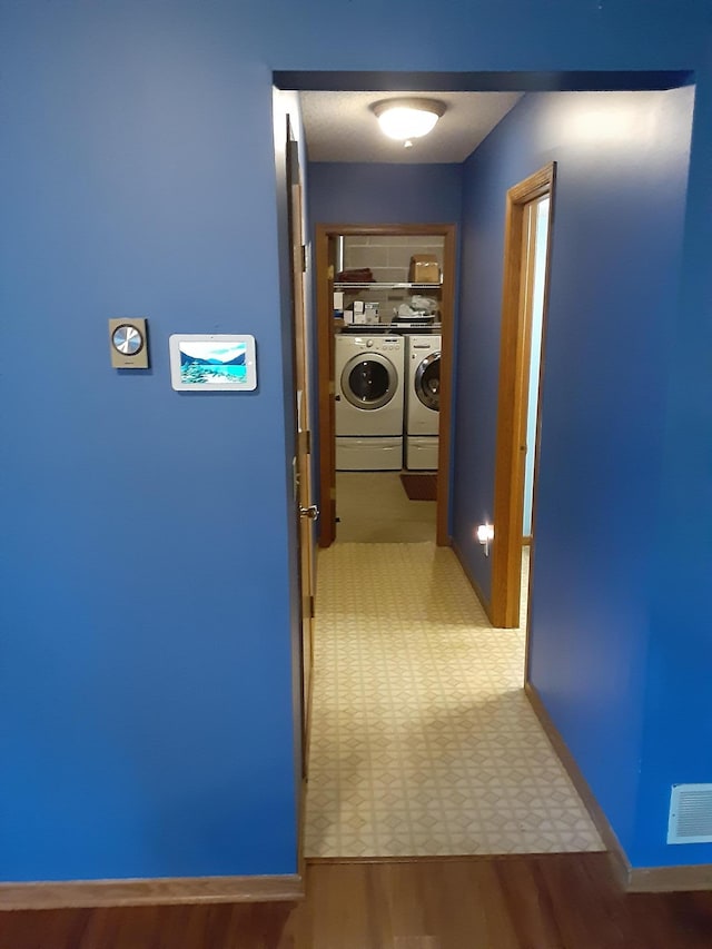 hallway featuring separate washer and dryer and light tile floors