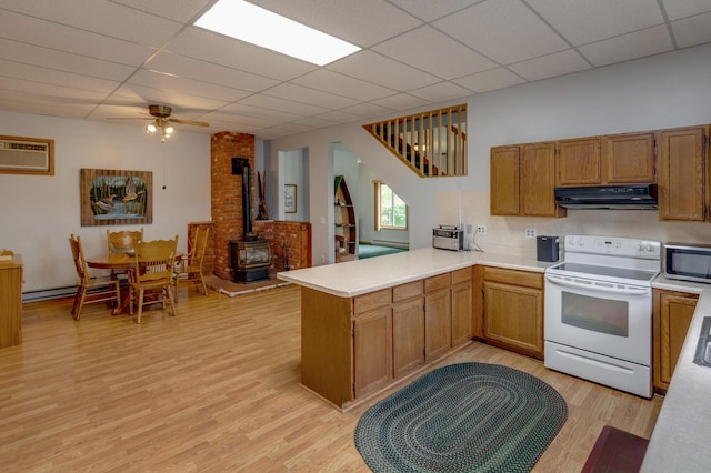 kitchen with range hood, kitchen peninsula, electric range, a wood stove, and ceiling fan