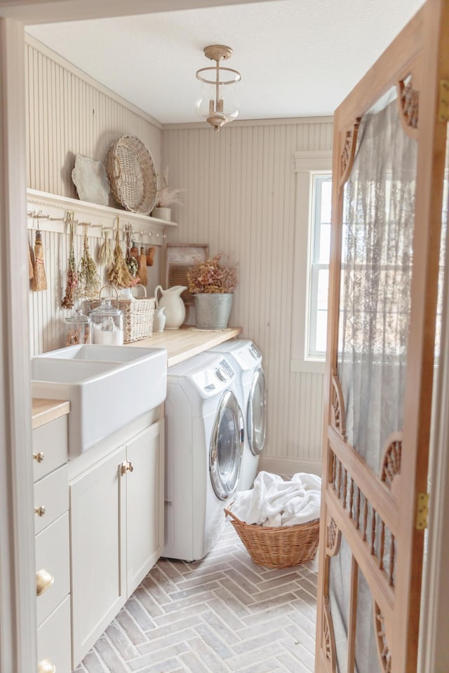 washroom featuring sink, washing machine and dryer, and cabinets