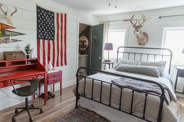 bedroom with wooden walls and hardwood / wood-style floors