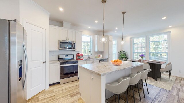 kitchen featuring hanging light fixtures, white cabinetry, appliances with stainless steel finishes, and a center island