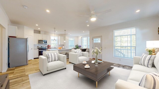 living room with ornamental molding, sink, ceiling fan, and light wood-type flooring