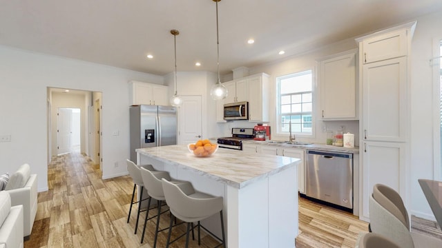 kitchen featuring decorative light fixtures, a kitchen island, appliances with stainless steel finishes, and white cabinetry