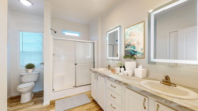 bathroom with double sink vanity, toilet, hardwood / wood-style floors, and an enclosed shower