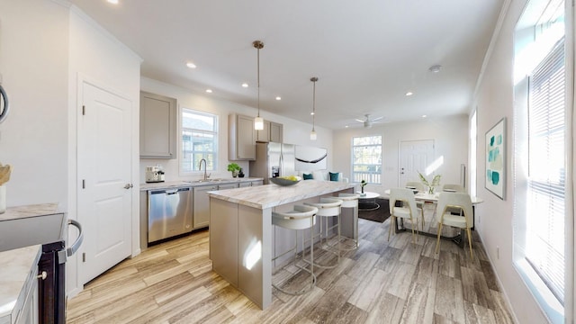 kitchen featuring appliances with stainless steel finishes, decorative light fixtures, plenty of natural light, gray cabinets, and a center island