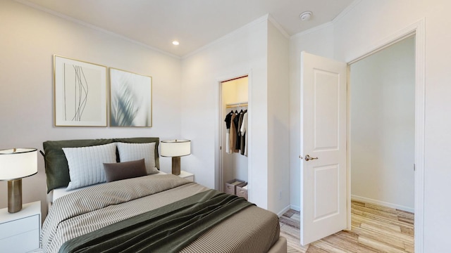 bedroom featuring a closet, a spacious closet, light hardwood / wood-style floors, and crown molding