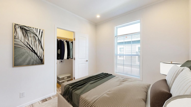 bedroom featuring light hardwood / wood-style floors, a closet, a spacious closet, and ornamental molding