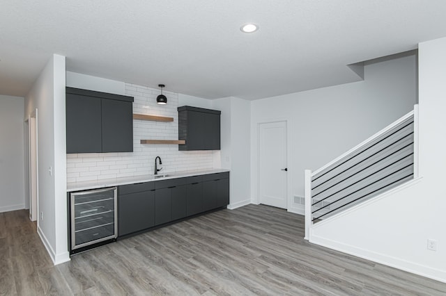 2811 Wildflower Ln SW, Rochester, MN 55902 - bar with stairway, wine cooler, backsplash, a sink, and light wood-style flooring