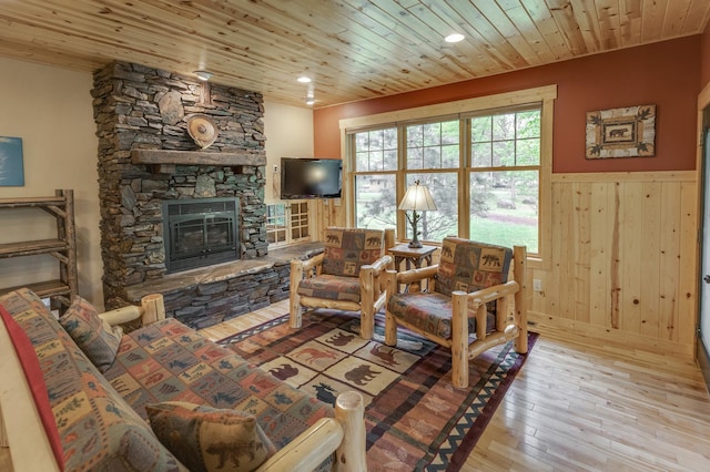 living room with wooden ceiling, a fireplace, light hardwood / wood-style floors, and wooden walls