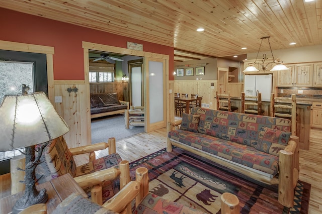 living room with ceiling fan, light hardwood / wood-style flooring, wood ceiling, and wooden walls