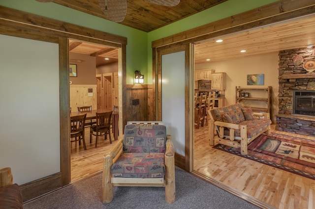 sitting room with hardwood / wood-style flooring, a stone fireplace, and wooden ceiling