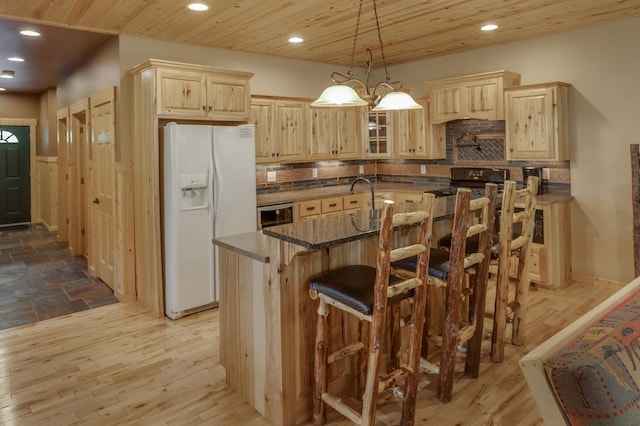 kitchen featuring tasteful backsplash, a breakfast bar, pendant lighting, light hardwood / wood-style flooring, and white fridge with ice dispenser