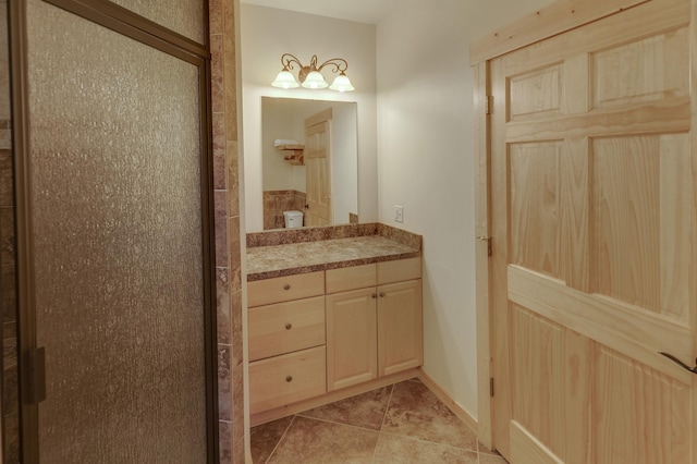 bathroom with a shower with door, vanity, and tile patterned flooring