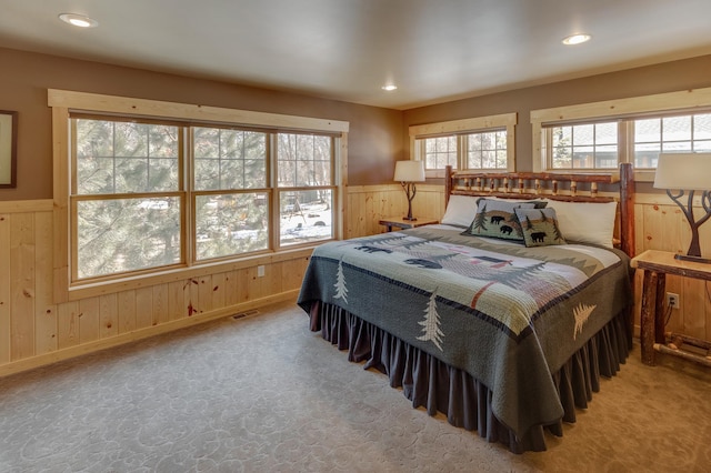 carpeted bedroom featuring wood walls