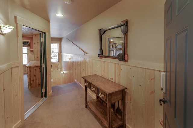 corridor featuring carpet floors and wooden walls