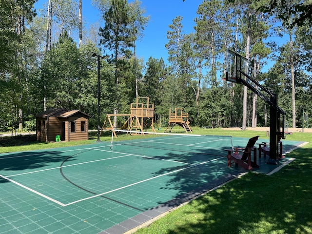 view of basketball court featuring a playground and a lawn