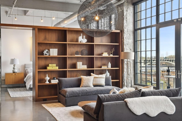 sitting room with concrete flooring, a towering ceiling, a healthy amount of sunlight, and track lighting