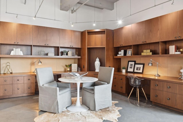 dining space with concrete flooring, beamed ceiling, and built in desk