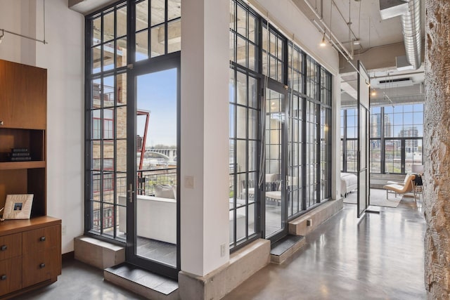 doorway with a high ceiling, concrete floors, and a wall of windows