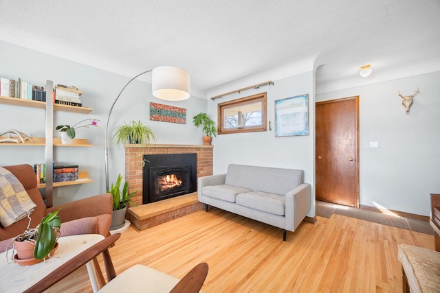 625 5th Ave S, Hopkins, MN 55343 - living room with light wood-type flooring, a brick fireplace, and a textured ceiling