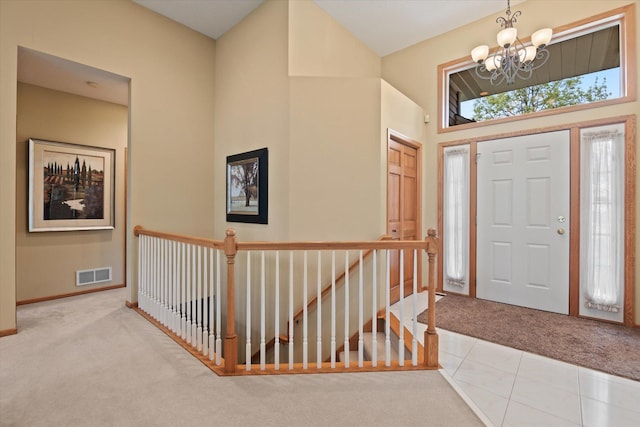 carpeted foyer entrance featuring a chandelier and a high ceiling