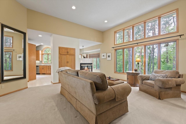 living room featuring a towering ceiling, sink, and light colored carpet