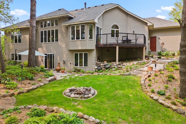 back of house featuring a deck, an outdoor fire pit, and a yard