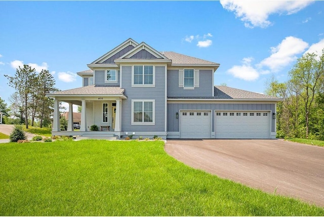 view of front of property featuring a porch, a front yard, and a garage