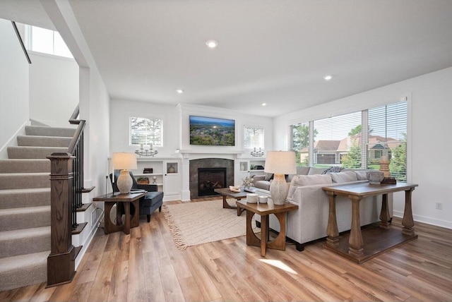 living room with built in shelves, light hardwood / wood-style floors, and a tiled fireplace