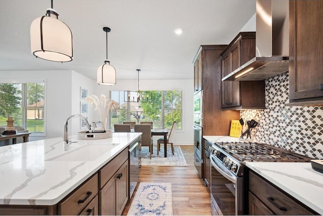 kitchen with a healthy amount of sunlight, tasteful backsplash, stainless steel appliances, and wall chimney exhaust hood