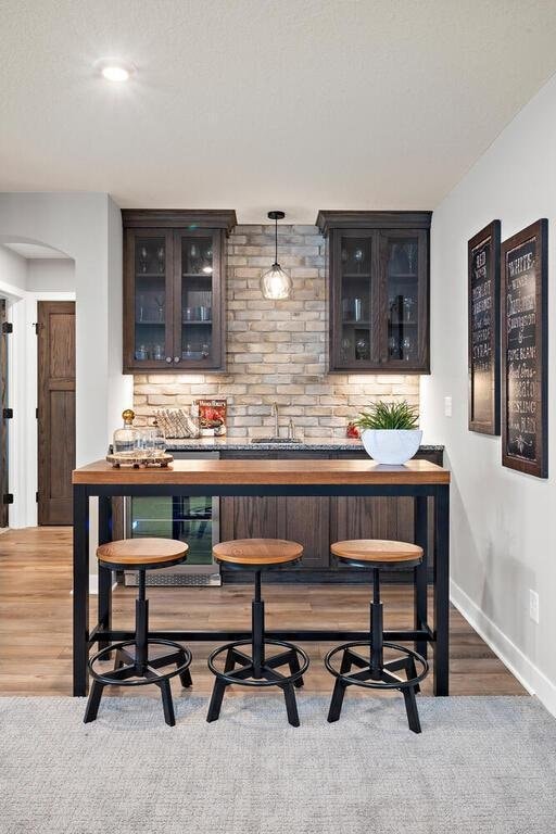 bar featuring hanging light fixtures, dark brown cabinets, dark colored carpet, and sink