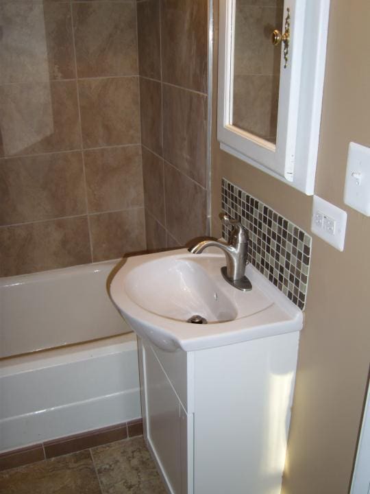 bathroom with vanity, tile floors, tasteful backsplash, and tiled shower / bath