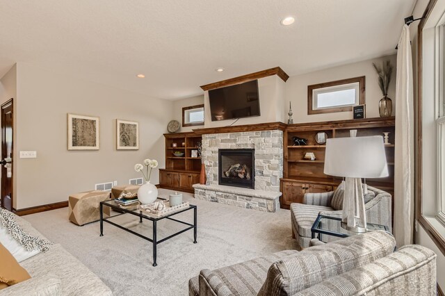 living room featuring light colored carpet and a stone fireplace