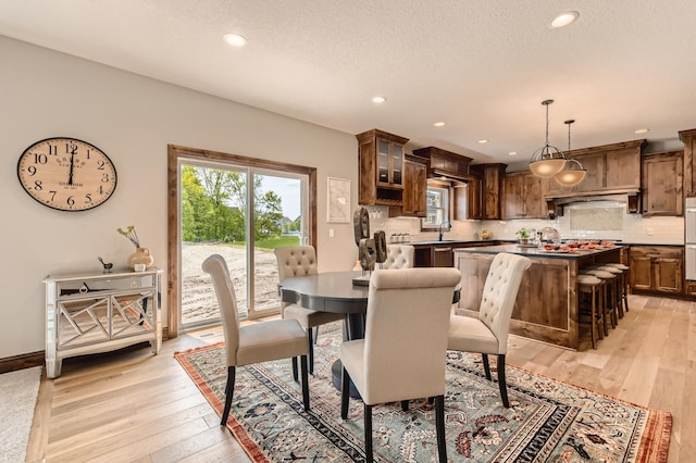 dining space with sink, light hardwood / wood-style floors, and a textured ceiling