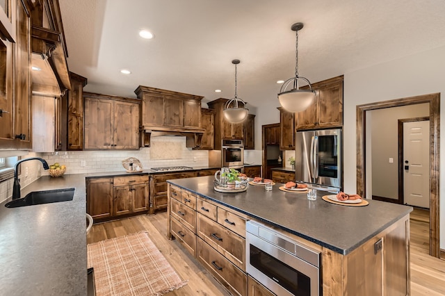 kitchen with hanging light fixtures, sink, a center island, decorative backsplash, and stainless steel appliances