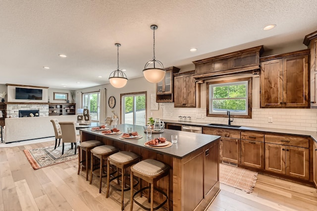 kitchen with a kitchen breakfast bar, hanging light fixtures, sink, light wood-type flooring, and a center island