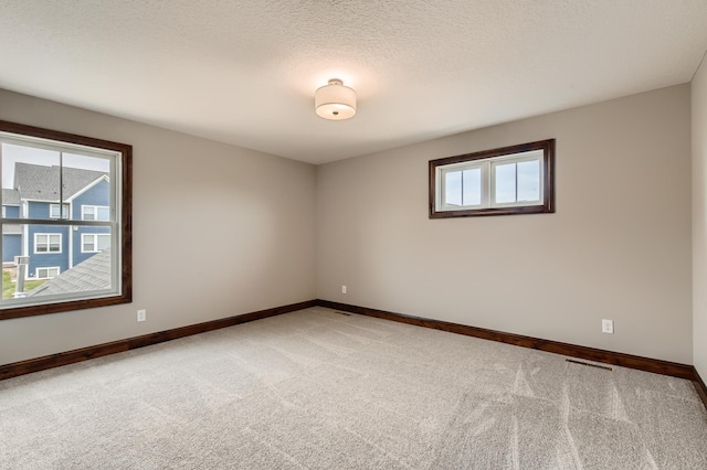 carpeted empty room with a textured ceiling