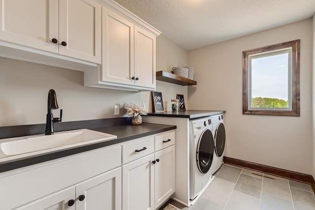 laundry area with sink, a textured ceiling, cabinets, and separate washer and dryer