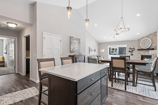 kitchen featuring pendant lighting, dark hardwood / wood-style floors, a stone fireplace, and a center island