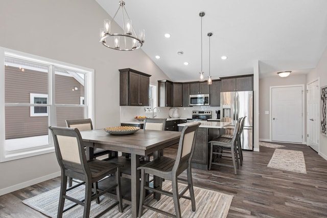 dining space with dark wood-type flooring, a chandelier, sink, and high vaulted ceiling