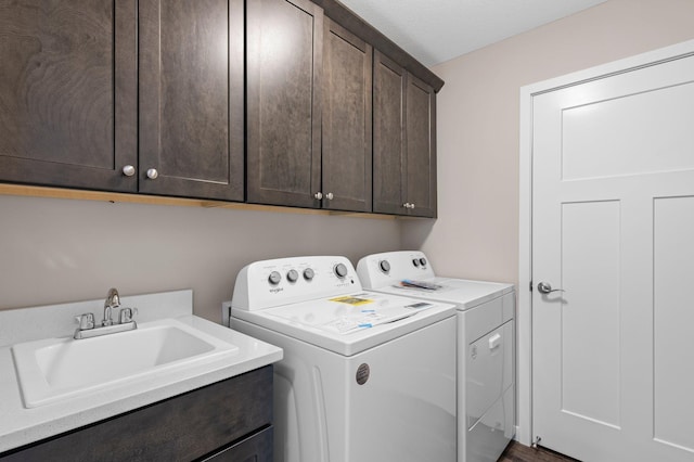 laundry area featuring cabinets, separate washer and dryer, and sink