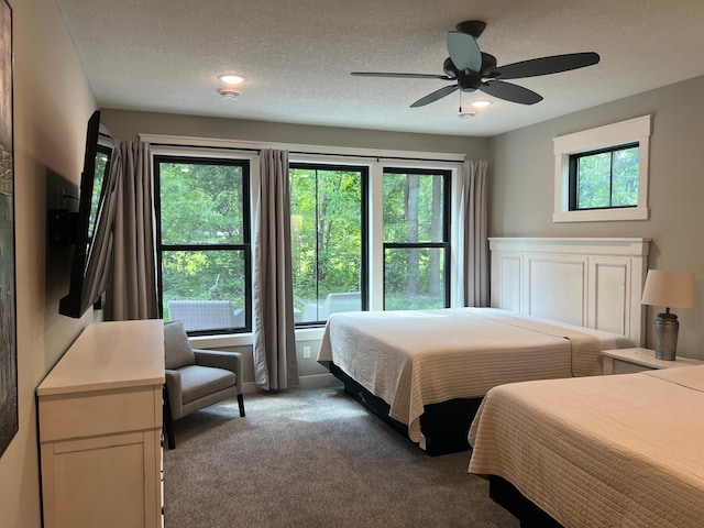 carpeted bedroom with ceiling fan and a textured ceiling