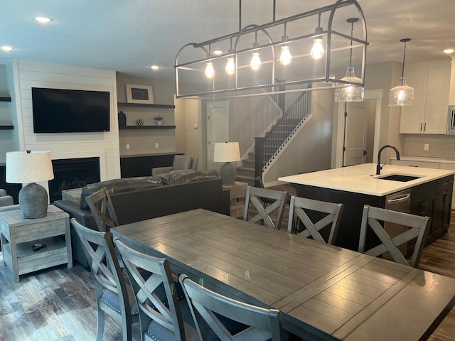 dining area with sink, a large fireplace, and dark hardwood / wood-style flooring