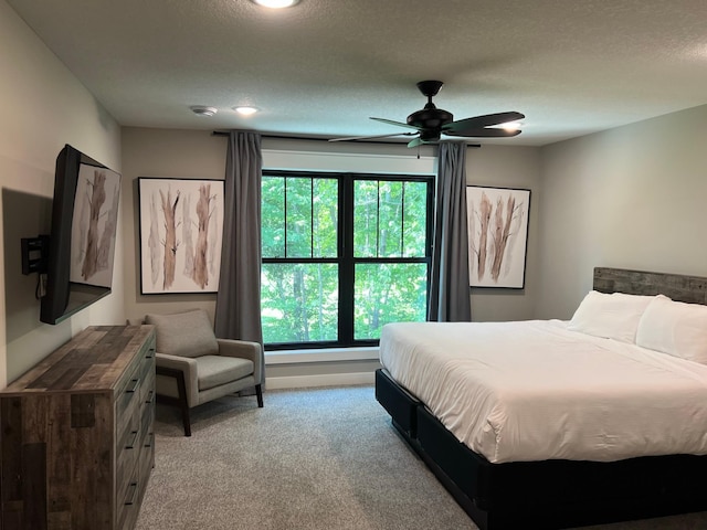 carpeted bedroom featuring multiple windows, a textured ceiling, and ceiling fan