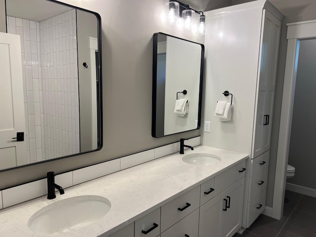 bathroom with toilet, dual bowl vanity, and tile floors