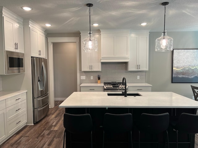 kitchen with white cabinets, dark hardwood / wood-style floors, stainless steel appliances, and pendant lighting